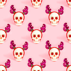White skull with party deer horns and xmas ball decorations repeat seamless pattern on light pink background. Christmas and New Year celebration wrapping paper design.