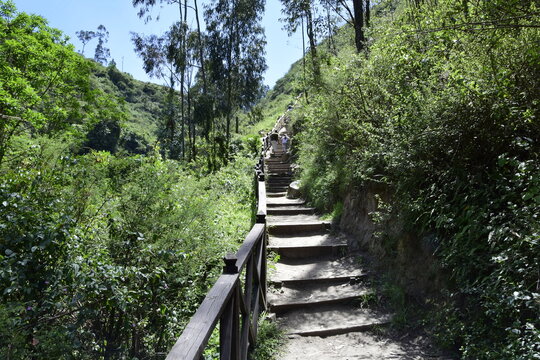 View of Peguche Waterfall in the mountains. It's surrounded by green forest full of vegetation. Ecuador