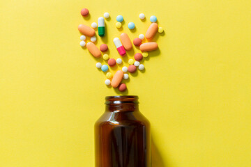 pills and pill bottles on yellow background,Brown medical glass drug bottle and some pills around...