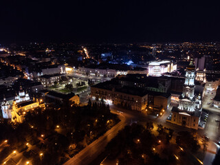 Fototapeta na wymiar Night lights illuminated city aerial view. City center square (Maidan Konstytutsii) with Dormition Cathedral, Svyato-Pokrovskyy Monastyr landmarks in Kharkiv, Ukraine