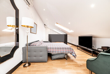 Apartment with sloping ceilings, unfolded sofa bed with checkered duvet, wooden floors and large skylights in the ceiling