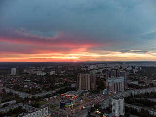 Fototapeta na wymiar Epic vibrant sunset aerial view in city, residential district. 23 serpnia Pavlovo Pole Kharkiv, Ukraine. Fly with majestic evening cloudscape and city lights