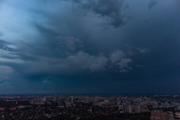 Aerial evening view on city with dramatic heavy sunset sky with clouds. Evening flight above city streets. Kharkiv, Ukraine city center park and residential district