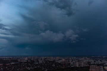 Fototapeta premium Aerial evening view on city with dramatic heavy sunset sky with clouds. Evening flight above city streets. Kharkiv, Ukraine city center park and residential district