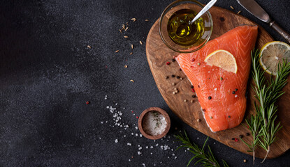 Uncooked raw salmon fish with herbs on dark background