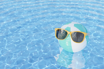 sunglasses on inflatable ball in swimming pool
