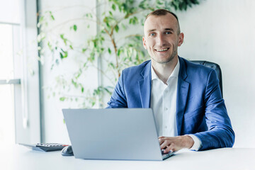 Business man portrait working on a laptop in an office.