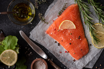 Uncooked raw salmon fish with herbs on dark background