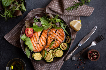 Cooked salmon fish with vegetables on dark background