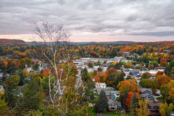 View of a shopping centre in a small town surrounded by a forest at the peak of autumn colours at sunset. Huntsville, ON, Canada.