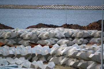 Plac budowy plaża materiały budowlane betonowe bloczki i stalowe pręty zwały piasku. 
