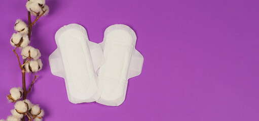 Two Sanitary napkin with wings and cotton flowers on purple background.top angle view