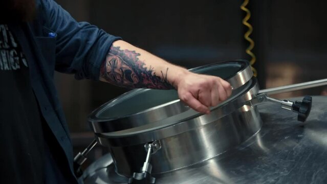 A man opens a cistern at a beer production, brewery