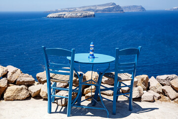Wooden blue table and chair on the shore of the blue sea. Seaside cafe.