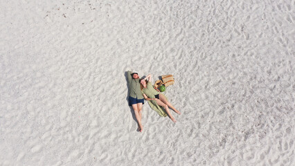 Aerial view of a young couple lying on the white sand. man and woman spend time together and travel...