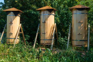 3 wooden beehives outdoors on sunny summer day. Apiculture