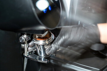 Close-up image of the coffee grinder machines in a coffee shop. Barista grinding freshly roasted coffee beans from a professional modern electric grinder into a powder. Cafe brewing Service Concept