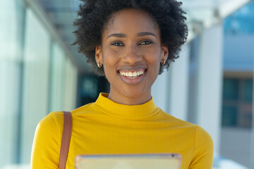 Fototapeta na wymiar Portrait of smiling young african american businesswoman with afro hairstyle holding tablet pc