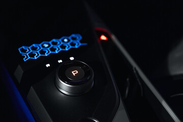 Rotary gear shift and glowing signs on car dashboard