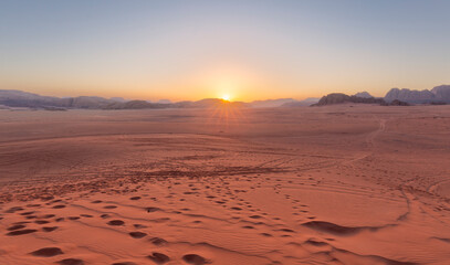 Panoramic view overlooking the red sand desert and Bedouin camp as seen with a cloudy golden sunset in Wadi Rum, Jordan