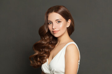 Naklejka premium Cute young model woman with long perfect curly hair and makeup. Beautiful female face with wavy hair on black background portrait