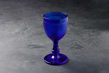 Elegant empty blue glass goblet on stone table closeup