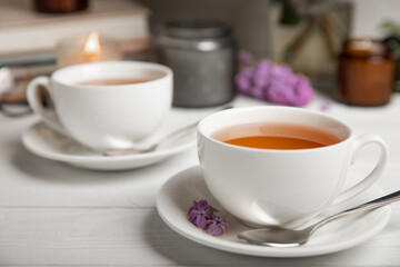 A cup of green tea against the background of a spring bouquet of lilacs on a textured gray background.Romantic composition with books and candles. Spring tea drink. Side view. Place to copy.