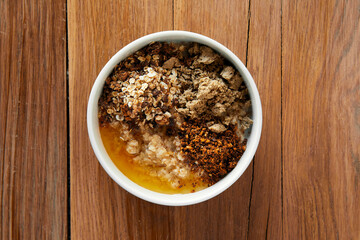 Oatmeal porridge with halva honey and nuts in bowl on table