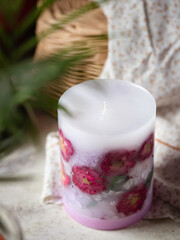 Handmade candles of a unique design, with different flowers, dry leaves on a light background. Candles made from organic wax, paraffin wax. Relaxation atmosphere. Luxurious lifestyle.
