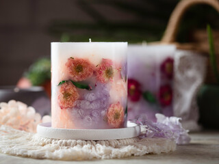Handmade candles of a unique design, with different flowers, dry leaves on a light background....