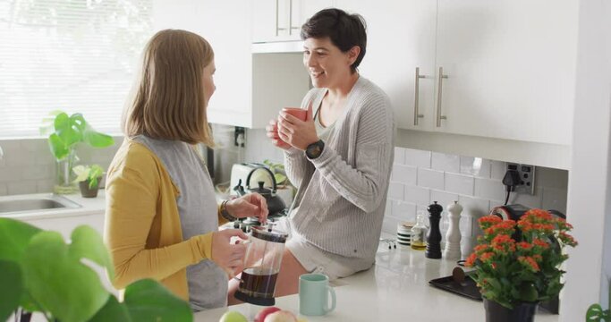 Caucasian lesbian couple having coffee together in the kitchen at home