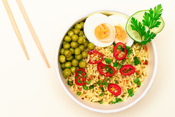 Beautiful Noodle Dish with Green Pea, Eggs, Red Hot Pepper and Greens with Chopsticks on White Background. Instant Noodles - Top View