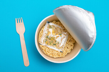 Opened Package with Uncooked Instant Noodles on Blue Background. Raw Pasta. Dry Asian Fast Food. Quick Lunch