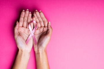 Cropped hands of african american mid adult woman holding breast cancer awareness ribbon, copy space
