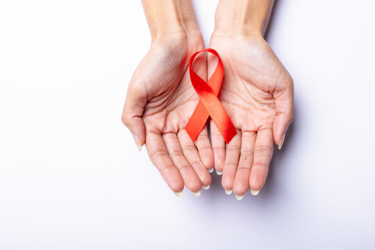 Cropped hands of african american mid adult woman with leukemia awareness ribbon on white background