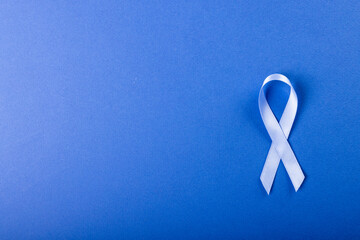 Directly above shot of stomach cancer awareness blue ribbon isolated against blue background