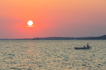 Beautiful view of sunset in the Mediterranean Sea with parked motor boat. Greece.