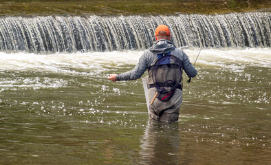 A fisherman catching fish in a rushing river