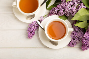 A cup of green tea against the background of a spring bouquet of lilacs on a textured gray background.Romantic composition with books and candles. Spring tea drink. Place to copy.