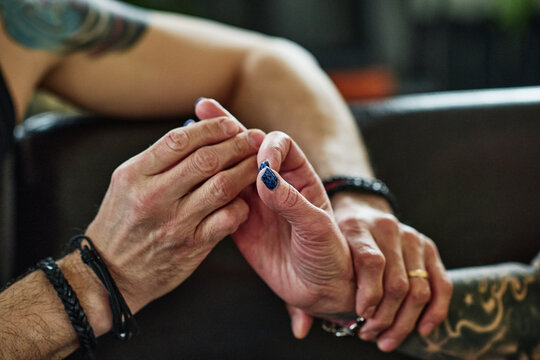 Horizontal close-up shot of unrecognizable man in love holding hand of his tattooed mature wife