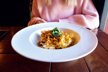 Salad in large plate and woman. Chicken meat, mushrooms, Korean-style carrots and potato. Closeup