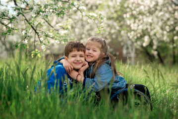 Naklejka na ściany i meble brother and sister are sitting and hugging in a blooming apple orchard