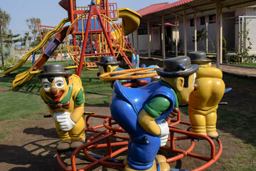 Bright colourful fun playground with slides and Clowns with hats colorful joker shaped roundabouts...