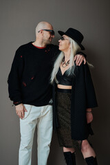 Vertical medium long studio shot of mature Caucasian man and woman in love wearing stylish clothes looking at each other