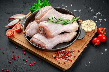 Fresh chicken drumsticks, legs with ingredients for cooking in a frying pan.