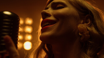 Sexy woman singing solo in microphone close up. Girl performing in studio lights