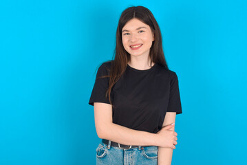 young caucasian woman wearing black T-shirt over blue background laughing.