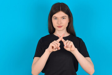young caucasian woman wearing black T-shirt over blue background has rejection angry expression...