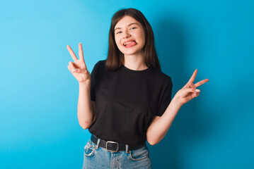 young caucasian woman wearing black T-shirt over blue background with optimistic smile, showing...