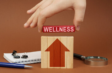 On a brown surface are office items, wooden blocks, in the hand is a red block with the inscription...